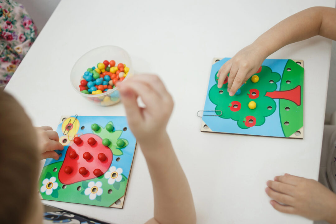 Toddlers playing multicolored educational games, mosaic and puzzles.
