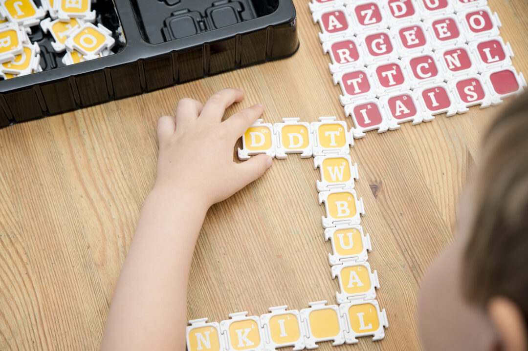 Preschool kid playing with alphabet tiles.