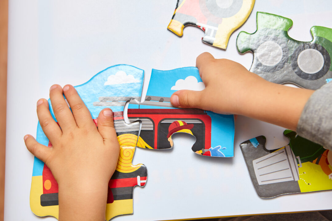 Child playing with toy car puzzle pieces.