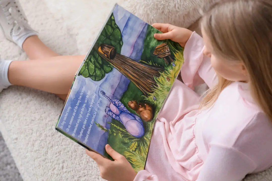 A little girl reading a book on the sofa at home.
